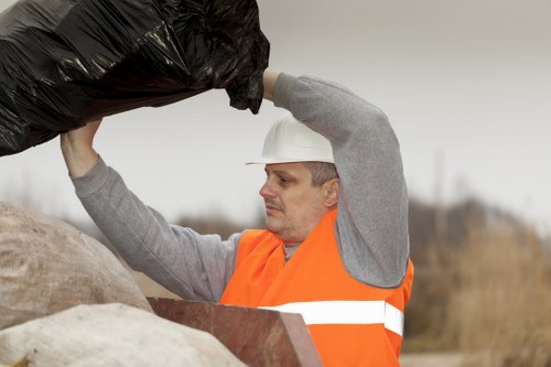 Workers wearing PPE handling waste at a skip delivery